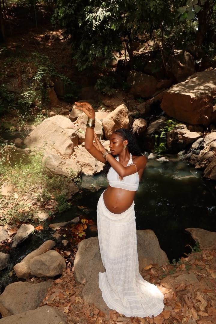 Maternity shoot in a white dress among rocks and a stream