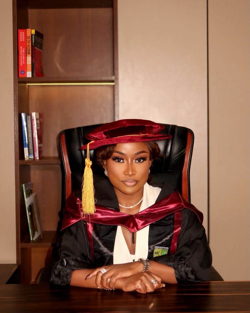 Graduation portrait in cap and gown, seated at a desk