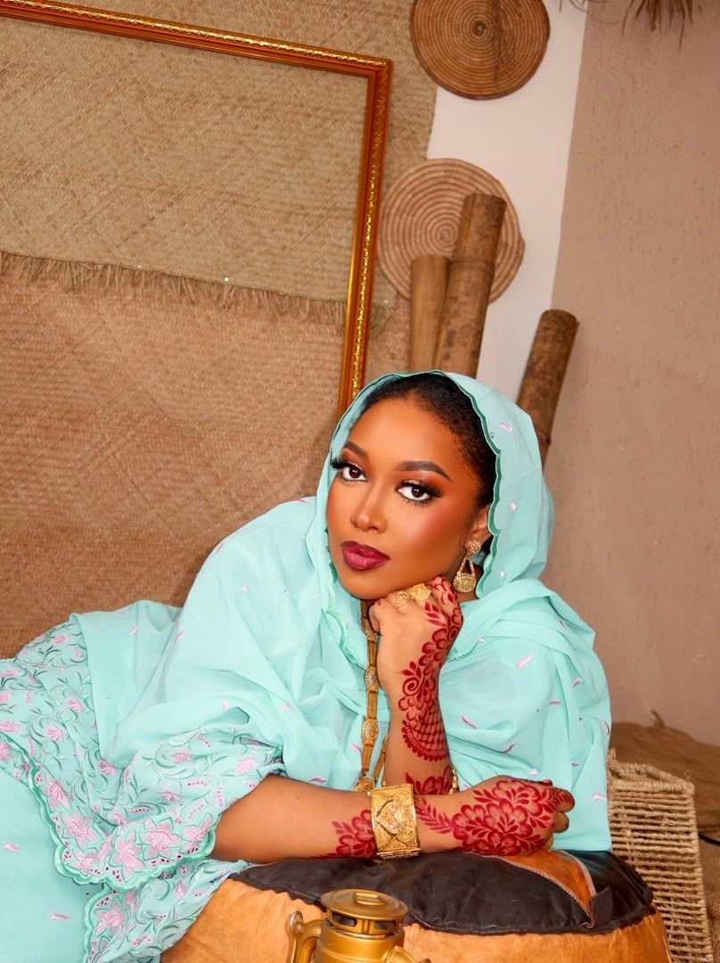 Woman in mint traditional attire with henna-decorated hands